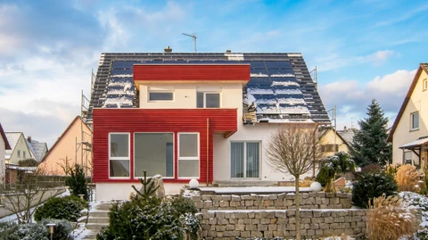 Maison individuelle rénovée en hiver, façade bicolore blanc et bardage bois rouge
